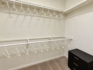 Ein Schrank mit zwei weißen Metallstangenregalen und einer schwarzen Kommode.