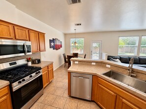 A modern kitchen with wooden cabinets, a stainless steel range, and a dishwasher. - Modern South Austin Townhome 3BR/2.5 BA + BBQ + Private Backyard (Austin)