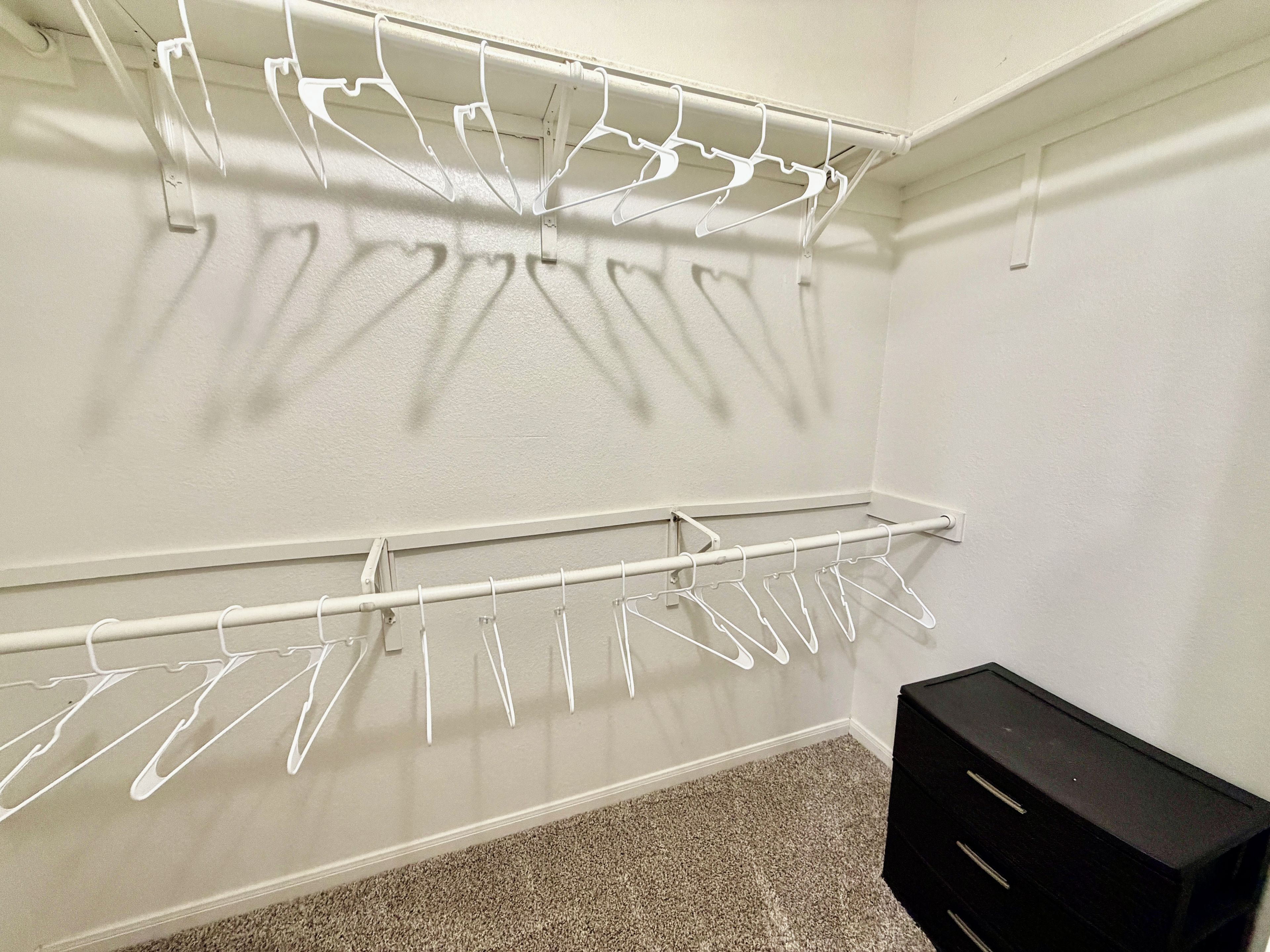 Un placard avec des cintres blancs et un meuble de rangement noir.