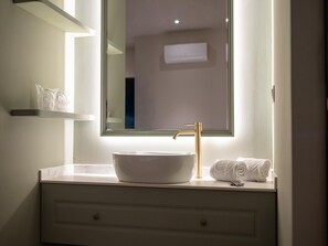 Ein Badezimmer mit einem weißen Waschbecken, einem goldenen Wasserhahn und einem Spiegel darüber.