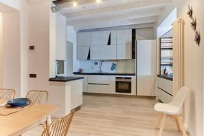 Eine moderne Küche mit weißen Schränken, einer schwarzen Arbeitsplatte und einem Holzespeisetisch mit Stühlen.