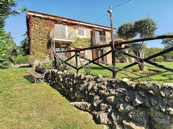 Un muro de piedra, un banco de madera y una casa con balcón.
