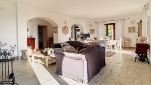 Un ampio soggiorno con divano, zona pranzo e cucina sullo sfondo.