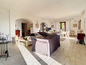 Un salón espacioso con un sofá, una zona de comedor y una cocina al fondo.