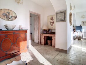 Una habitación con un armario de madera, un cuadro, un espejo y una cesta de mimbre.