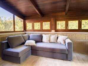 Un divano angolare componibile con un cuscino, una parete in pietra e un soffitto in legno.