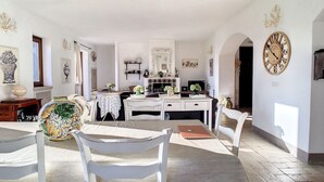 Zona pranzo con tavolo, sedie e cucina sullo sfondo.