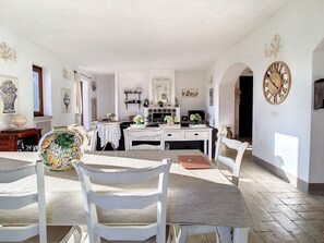 Un comedor con mesa, sillas y una cocina al fondo.