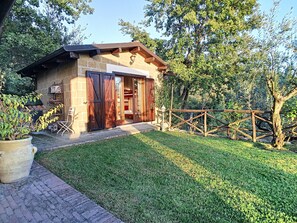 Una baita rustica con facciata in mattoni, ampie porte scorrevoli in vetro e un'uscita su un patio in legno.
