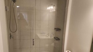 Ein modernes Badezimmer mit einer Duschkabine, einer Toilette, einem Waschbecken und einem kleinen dekorativen Gegenstand auf der Ablagefläche.