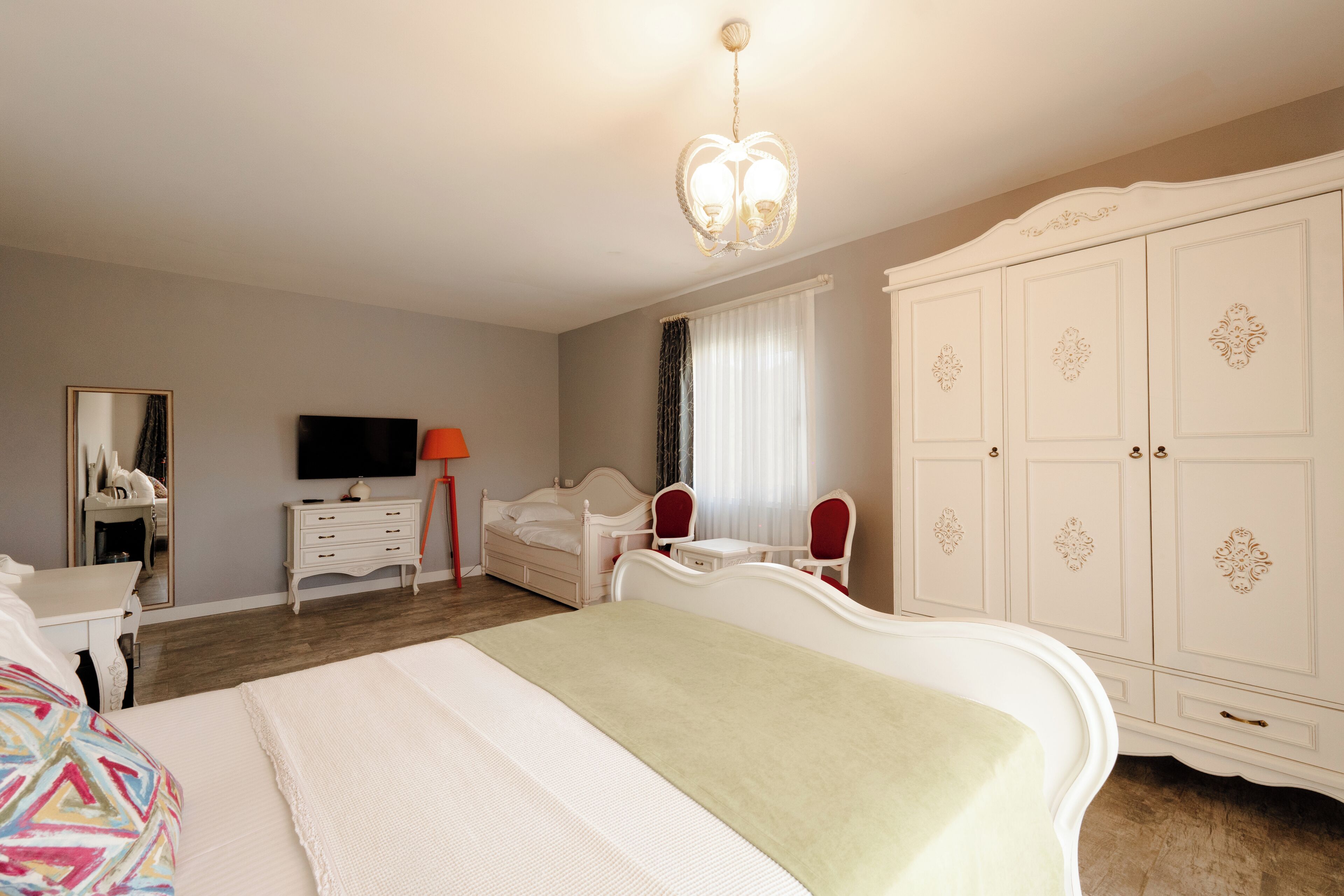 Un dormitorio con cama, cómoda, televisor, espejo y armario.