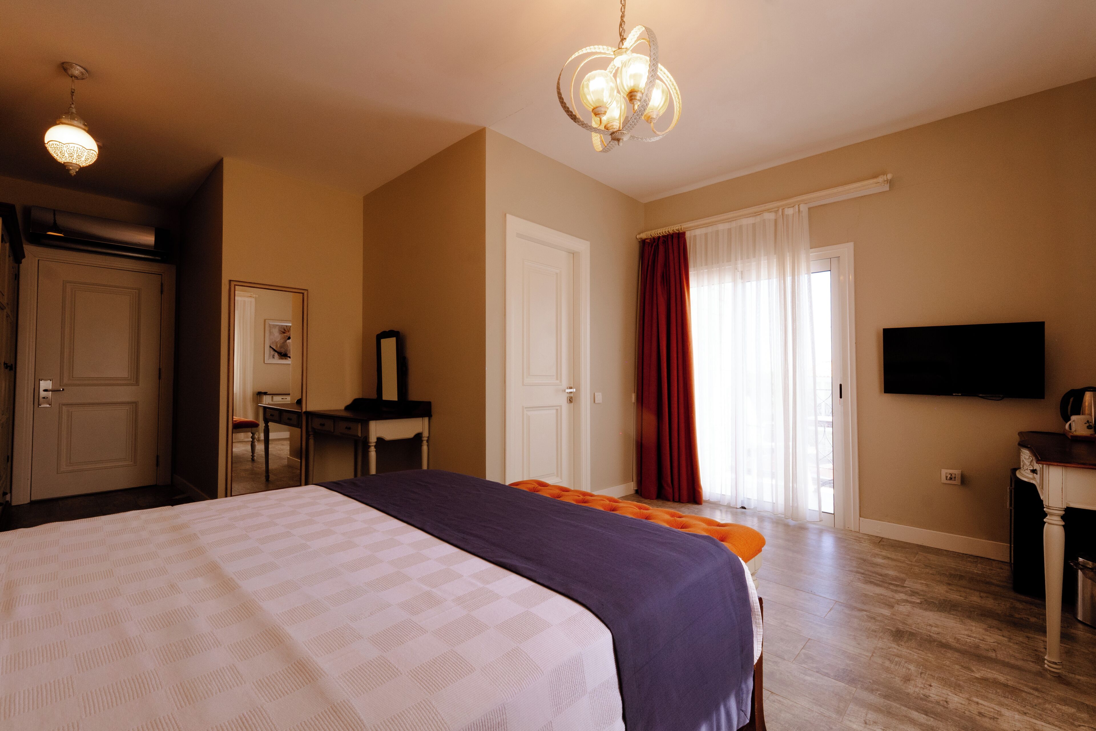 Habitación de hotel con una cama grande, un escritorio, una silla, un televisor y una ventana con cortinas.