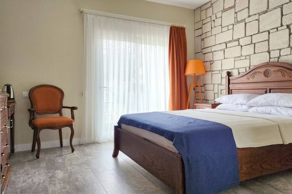 A bedroom with a wooden bed, a chair, a nightstand, and a lamp.