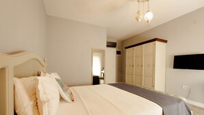 Un dormitorio con una cama, un armario y un televisor montado en la pared.