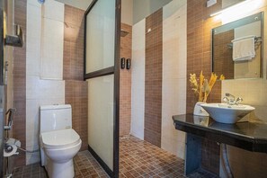 A bathroom with a toilet, shower, and sink, featuring tiled walls and a mirror. - River View Resort (Haridwar)