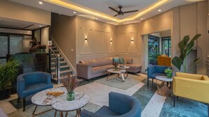 A modern interior with a sofa, chairs, a coffee table, and a staircase. - River View Resort (Haridwar)