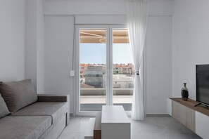 Een moderne woonkamer met een bank, een salontafel, een televisie en een schuifdeur naar een buitenbalkon.