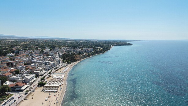Vista aérea de una ciudad costera con playa, edificios y cielo despejado.