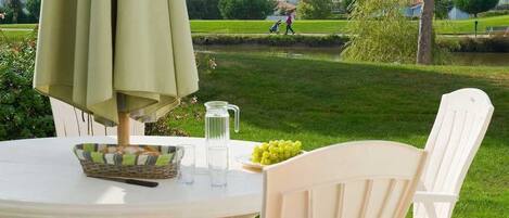 A round table with a woven basket, a pitcher, and a plate of grapes.