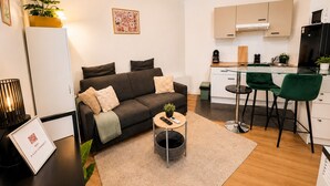 Un appartement moderne comprenant un canapé, une table basse et un petit coin cuisine.