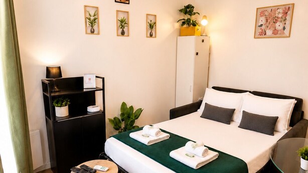 Une chambre d’hôtel comprenant un lit, des tables de chevet, un bureau, une chaise, une armoire, un miroir et une petite plante en pot.