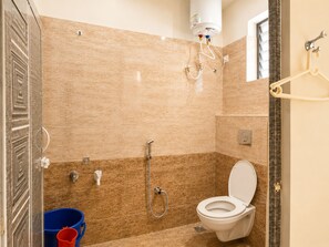 A bathroom with a toilet, shower, and a water heater mounted on the wall. - Hotel Golden Stay (Bengaluru)