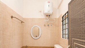 Un baño con inodoro, ducha, secamanos y calentador de agua.