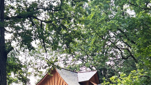 Een houten hut met een balkon, een trap en een raam.