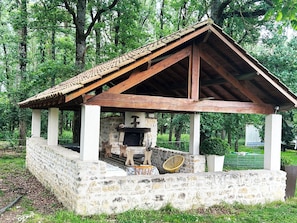 Una construcción de piedra con techo de tejas, chimenea y banco de madera.