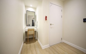 A hallway with a white door, a small mirror, and a white sink with a chair. - Hotel Foma (Changwon)
