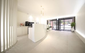 A modern kitchen with a central island, white cabinetry, and a large window providing natural light. - Hotel Foma (Changwon)