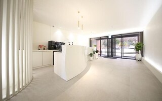 A modern kitchen with a central island, white cabinetry, and a large window providing natural light.