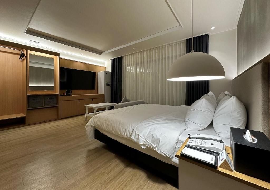 Una habitación de hotel moderna con una cama grande, un escritorio, un televisor y un armario.