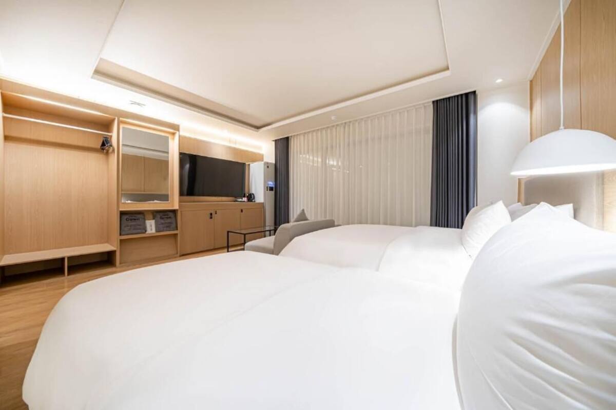 A hotel room with a large bed, a wardrobe, a desk, and a television.