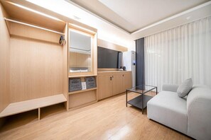 A modern hotel room with a wooden wardrobe, a glass coffee table, and a grey sofa. - Hotel Foma (Changwon)