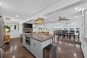A spacious kitchen with a central island, a dining area with a large table, and a view of the outdoors. - Heron's Rest – Lakefront Home w/ Hot Tub, Kayaks & Game Room (Pocono Lake)