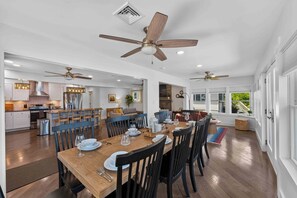 A spacious dining area with a wooden table set for six, surrounded by chairs, with ceiling fans and a view to the outside. - Heron's Rest – Lakefront Home w/ Hot Tub, Kayaks & Game Room (Pocono Lake)