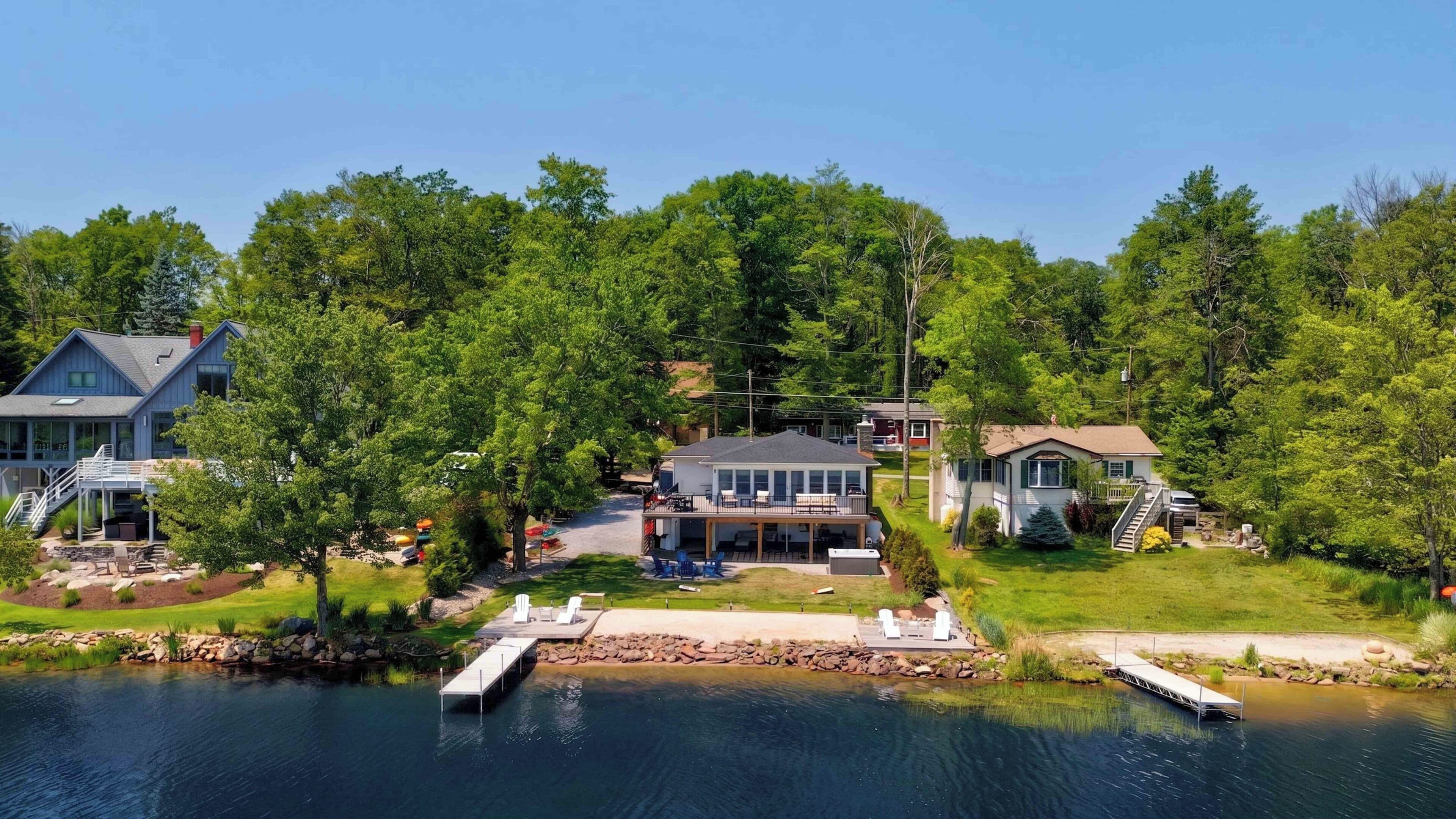 A lakeside property with a dock, a central house, and two additional buildings.