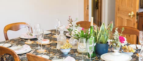 A dining table set with plates, glasses, and a centerpiece with flowers and a candle.