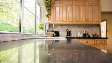 A kitchen with wooden cabinets, a stainless steel sink, and a window with a view of greenery.