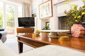 A living room with a wooden table, a television, and a pink vase with flowers. - Whitebeams (Canterbury)