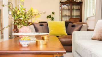 A wooden coffee table with a bowl of fruit, a vase with flowers, and a decorative plate.