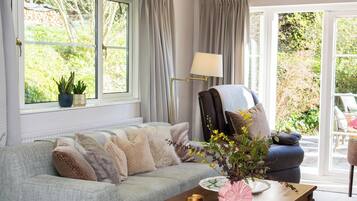 A cozy living room with a sofa, a chair, a table with a vase, and a lamp.