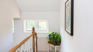 Eine Treppe mit einer Holzhandläufe, ein Blumentopf auf einem kleinen Tisch und ein gerahmtes Bild an der Wand.