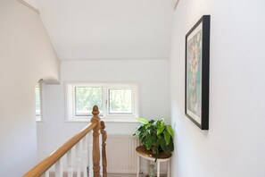 Eine Treppe mit einer Holzhandläufe, ein Blumentopf auf einem kleinen Tisch und ein gerahmtes Bild an der Wand.
