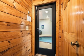 Eine Holztür, die zu einem Raum mit einem Pool führt.