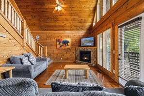 Ein rustikales Holzblockhaus-Interieur mit einer Couch, einem Holztisch, einem Kamin und einem Fernseher.