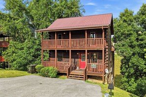 Eine zweistöckige Blockhütte mit roter Tür, einem Balkon und einer Satellitenschüssel.