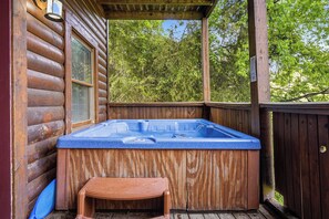 Eine Holzhütte mit Whirlpool, einem Fenster mit Jalousien und einer Holzterrasse.