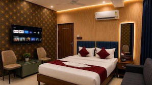 Una habitación de hotel con cama, televisor montado en la pared, escritorio, silla y sofá.